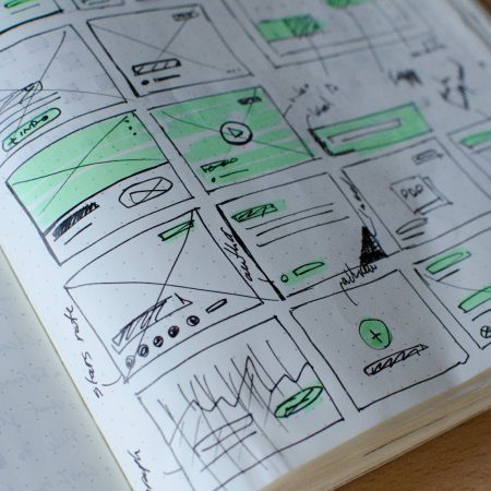 A notebook of prototype sketches lays open.