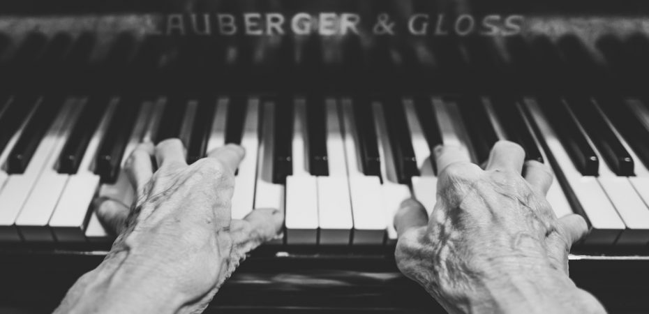 A piano being played by aged hands.